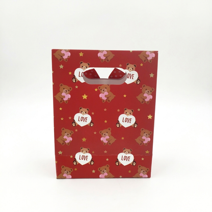 Red gift bag with teddy bear and heart designs on a white background