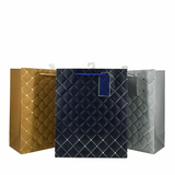 Three quilted paper bags in gold, black, and silver on a white background