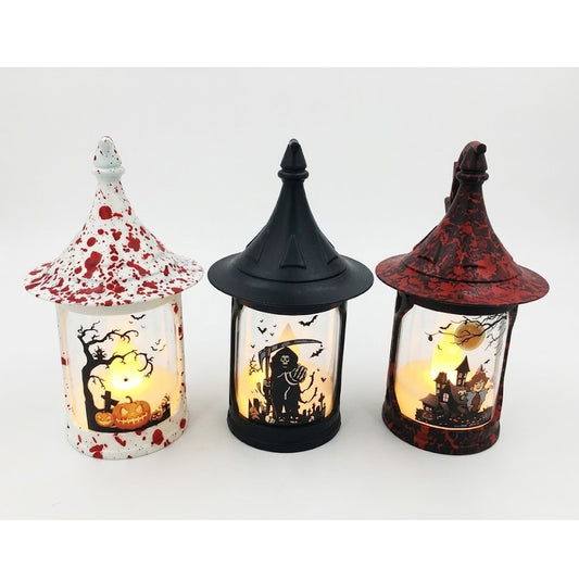 Three Halloween witch-house lanterns with pointed roofs, shown side by side on a white background. The left lantern is white with red splatter and a pumpkin-and-tree design, the middle lantern is black with a skeleton-and-horror scene, and the right lantern is dark red with a haunted-house design.