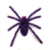 A purple tinsel spider decoration with red eyes, photographed against a plain white background.