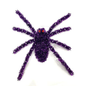 A purple tinsel spider decoration with red eyes, photographed against a plain white background.