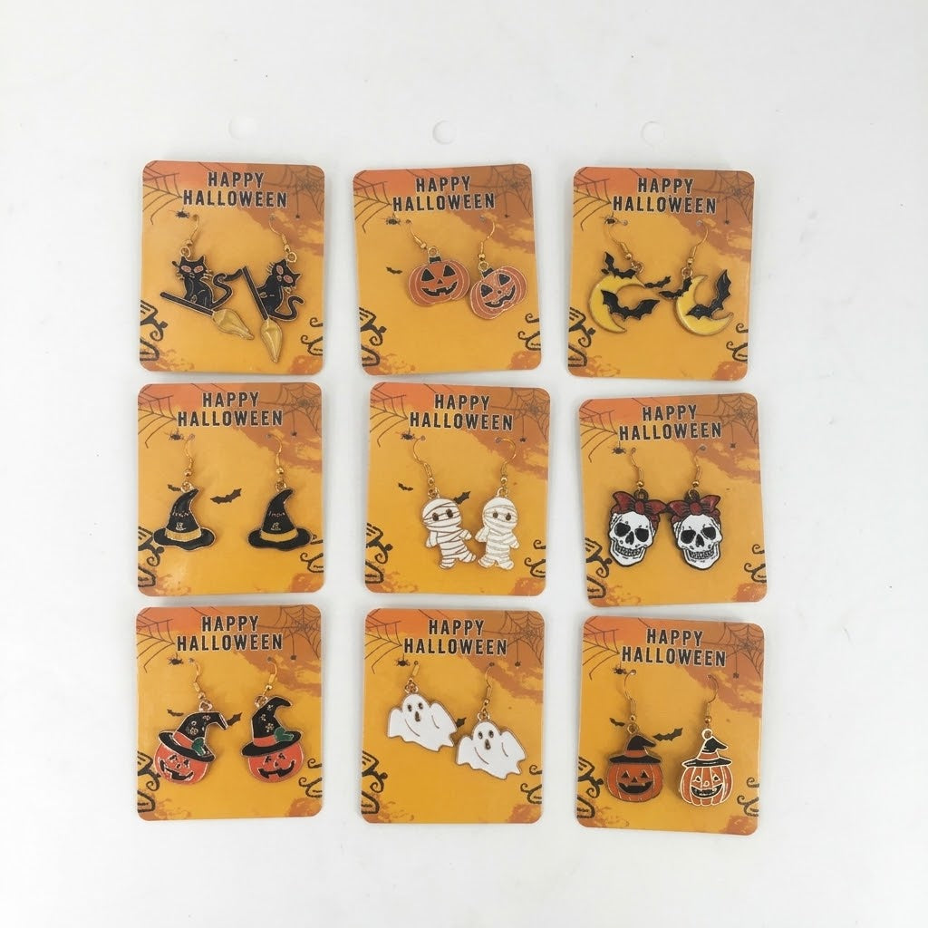 Nine pairs of Halloween-themed dangle earrings displayed on matching orange backing cards against a plain white background. The designs include witches, pumpkins, mummies, skulls, ghosts, and a witch-and-pumpkin pair, each with 'HAPPY HALLOWEEN' printed on its card.