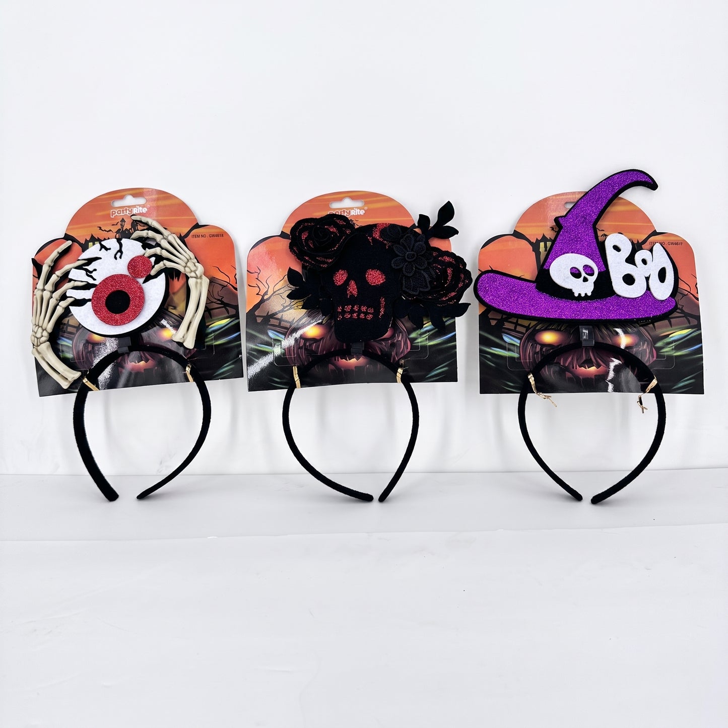 Three Halloween headbands displayed side by side on their retail backing cards. The left headband features a skeleton hand holding a large red and black eye.