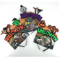Two pairs of Halloween novelty glasses on display cards against a white background. One pair features a black and purple pumpkin-and-tree design with orange 'HALLOWEEN' text, and the other features a green witch-hat pumpkin-and-tree design with orange 'HALLOWEEN' text.
