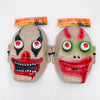 Two plastic Halloween clown masks with attached retail hangers, shown side by side on a plain white background. One mask is beige with black eye makeup, red nose, and red mouth details; the other is beige with green eye makeup and red mouth details.