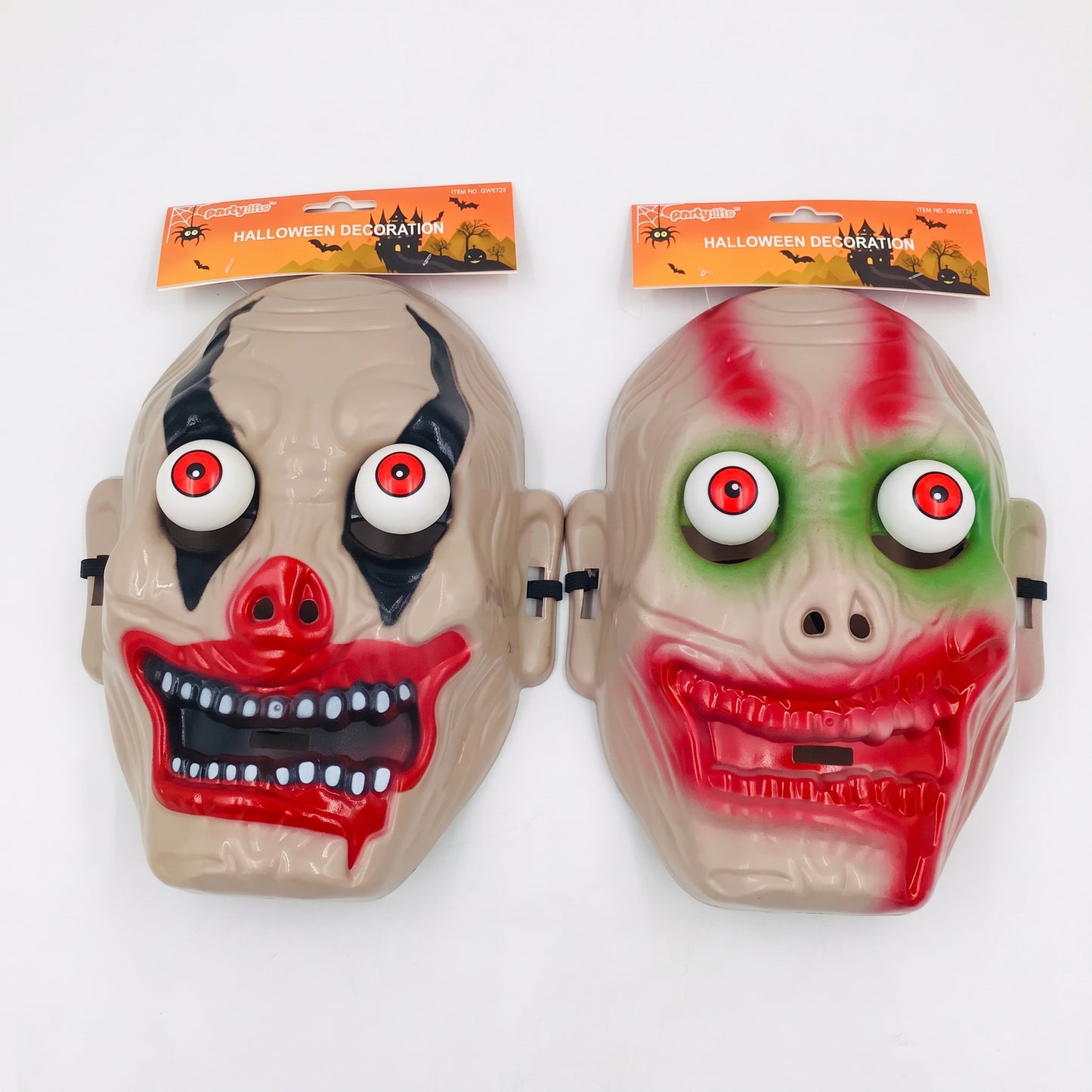 Two plastic Halloween clown masks with attached retail hangers, shown side by side on a plain white background. One mask is beige with black eye makeup, red nose, and red mouth details; the other is beige with green eye makeup and red mouth details.
