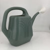 Green watering can with a white handle on a light gray background