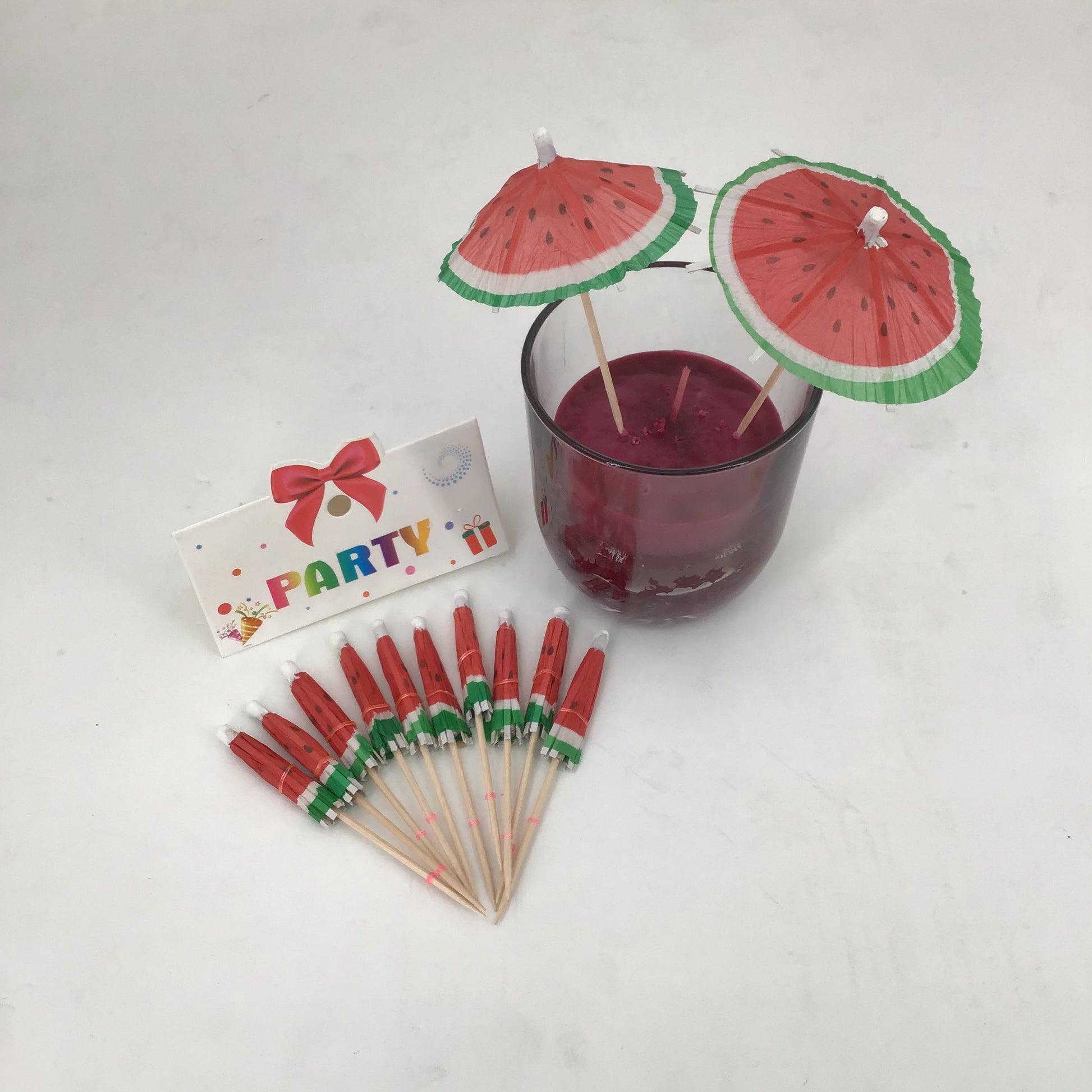 watermelon umbrella drink stirrers with a glass of red drink and 'Party' sign on a white background