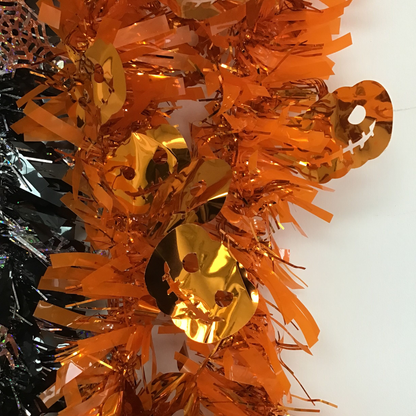 Orange metallic tinsel garland with shiny gold circular ornaments, photographed against a plain white background.