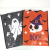 Two Halloween-themed plastic tote bags laid flat on a white surface. The left bag is dark gray with a white ghost, black spider, bats, and stars.