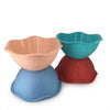 Four flower-shaped plastic mixing bowls stacked in pairs, shown in peach, teal, and red on a white background.