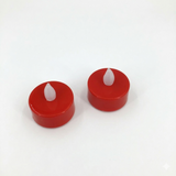Two red candles with white wicks on a white background